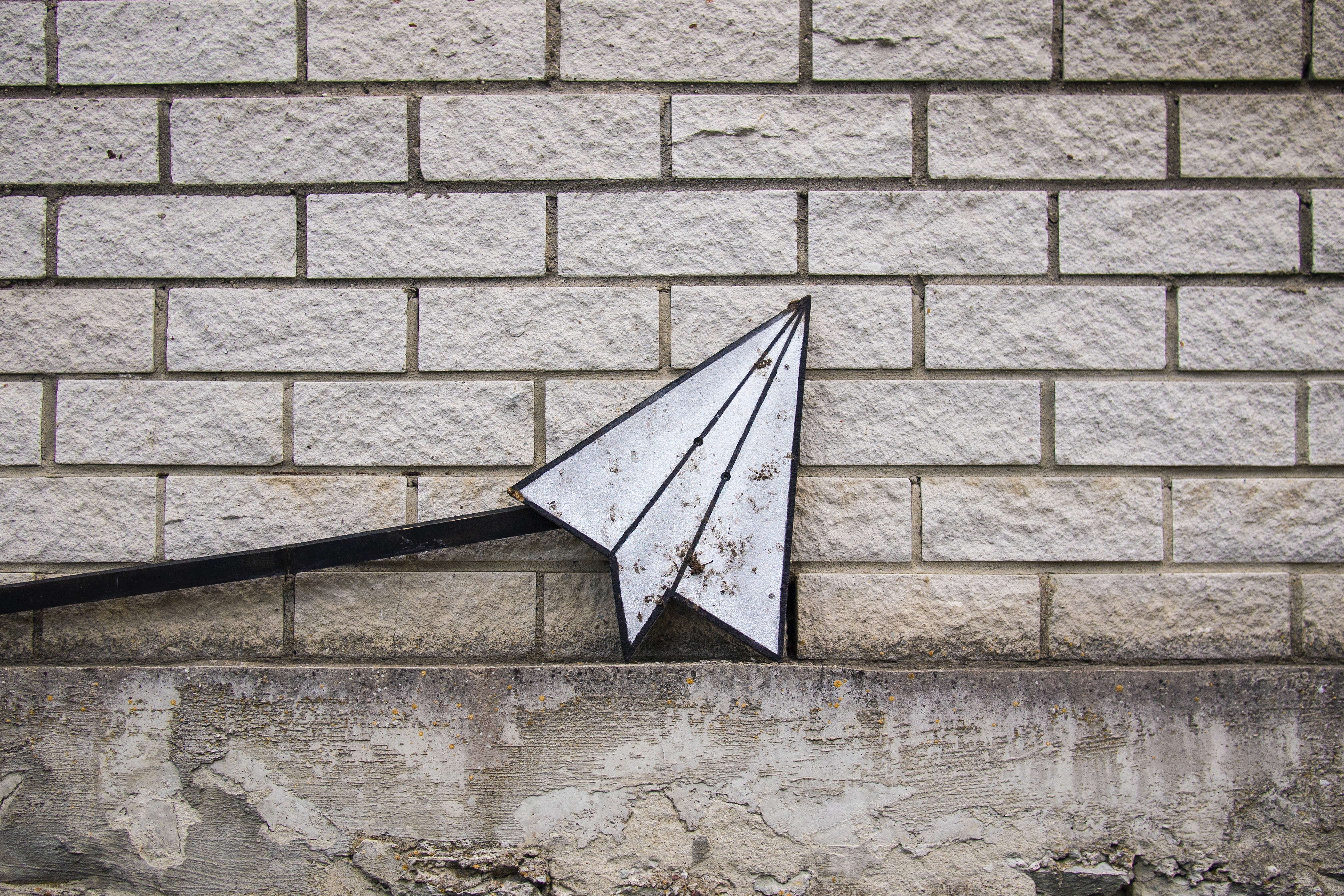 a paper plane in front of a bricked wall